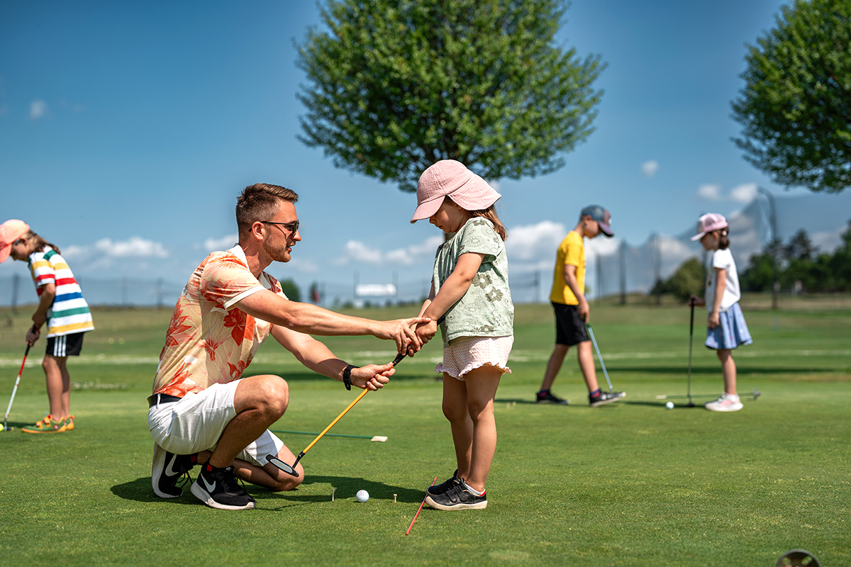 trenér vysvětluje dětem patování při golfovém tréniku na BICZ Park Golfu
