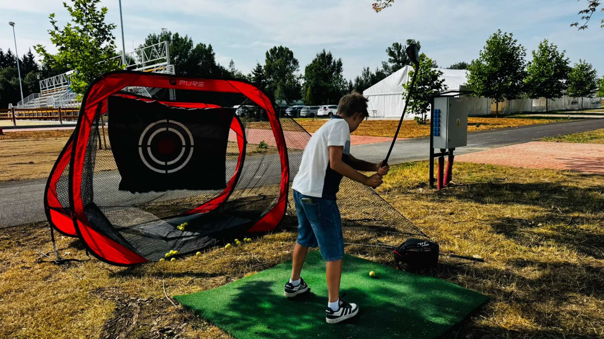 Návštěvníci si zkoušejí golf ve stánku Park Golf Hradec Králové během 3. kvalifikace na Velkou pardubickou na pardubickém závodišti.